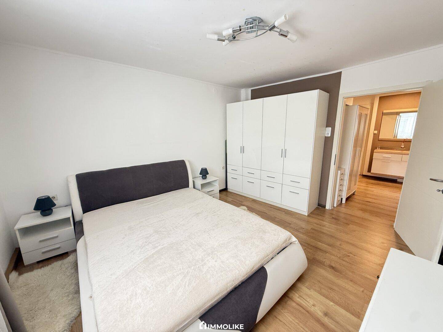 Schlafzimmer mit Doppelbett, großem Kleiderschrank und Laminatboden.