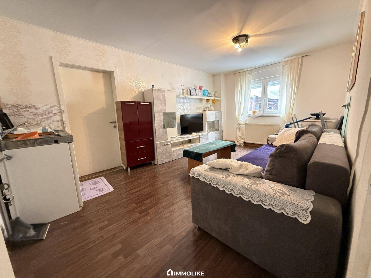 Gemütliches Wohnzimmer mit Sofa, Mediamöbel und Laminatboden.