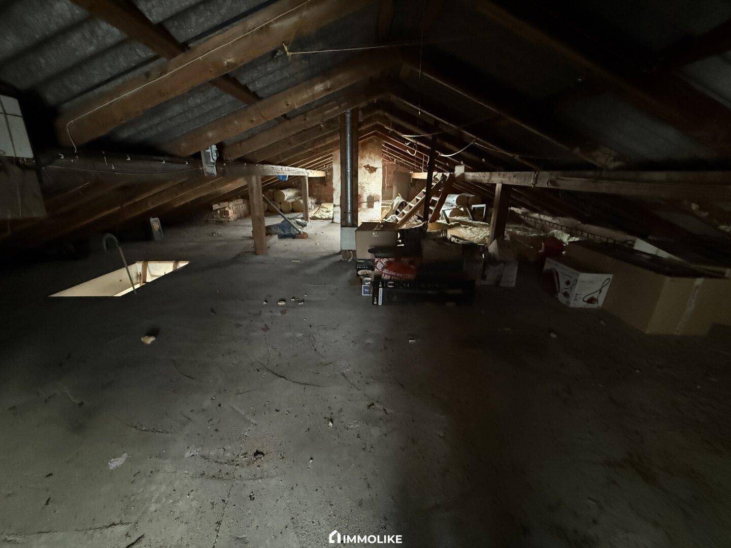 Unausgebauter Dachboden mit sichtbaren Holzbalken und Lagerflächen.