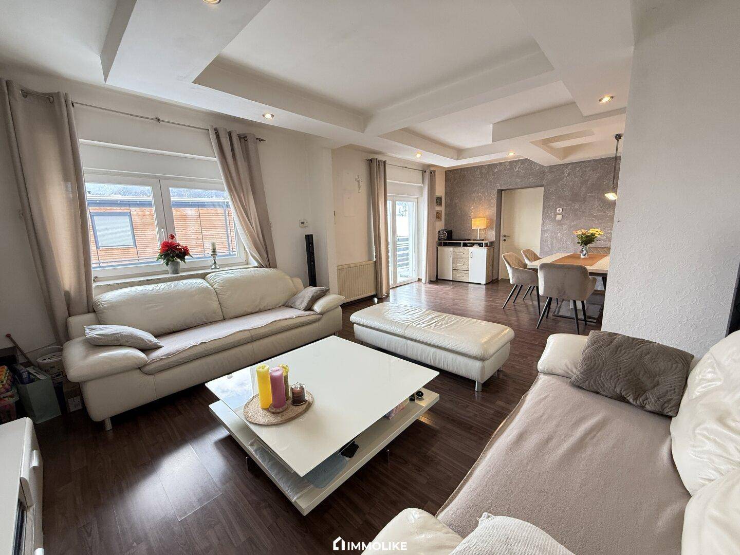 Offener Wohn-Essbereich mit bequemen Sofas und modernem Laminatboden.