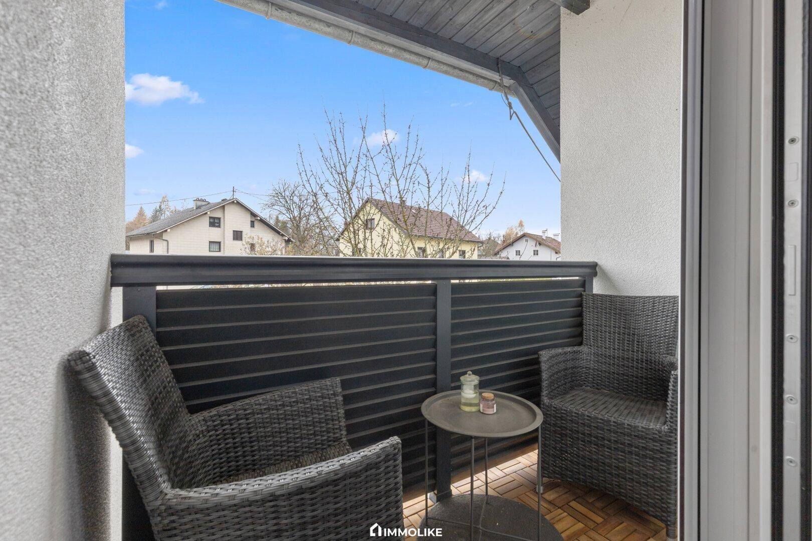 Kleiner Balkon mit Sitzgelegenheiten und Blick auf die umliegenden Häuser und Landschaft.