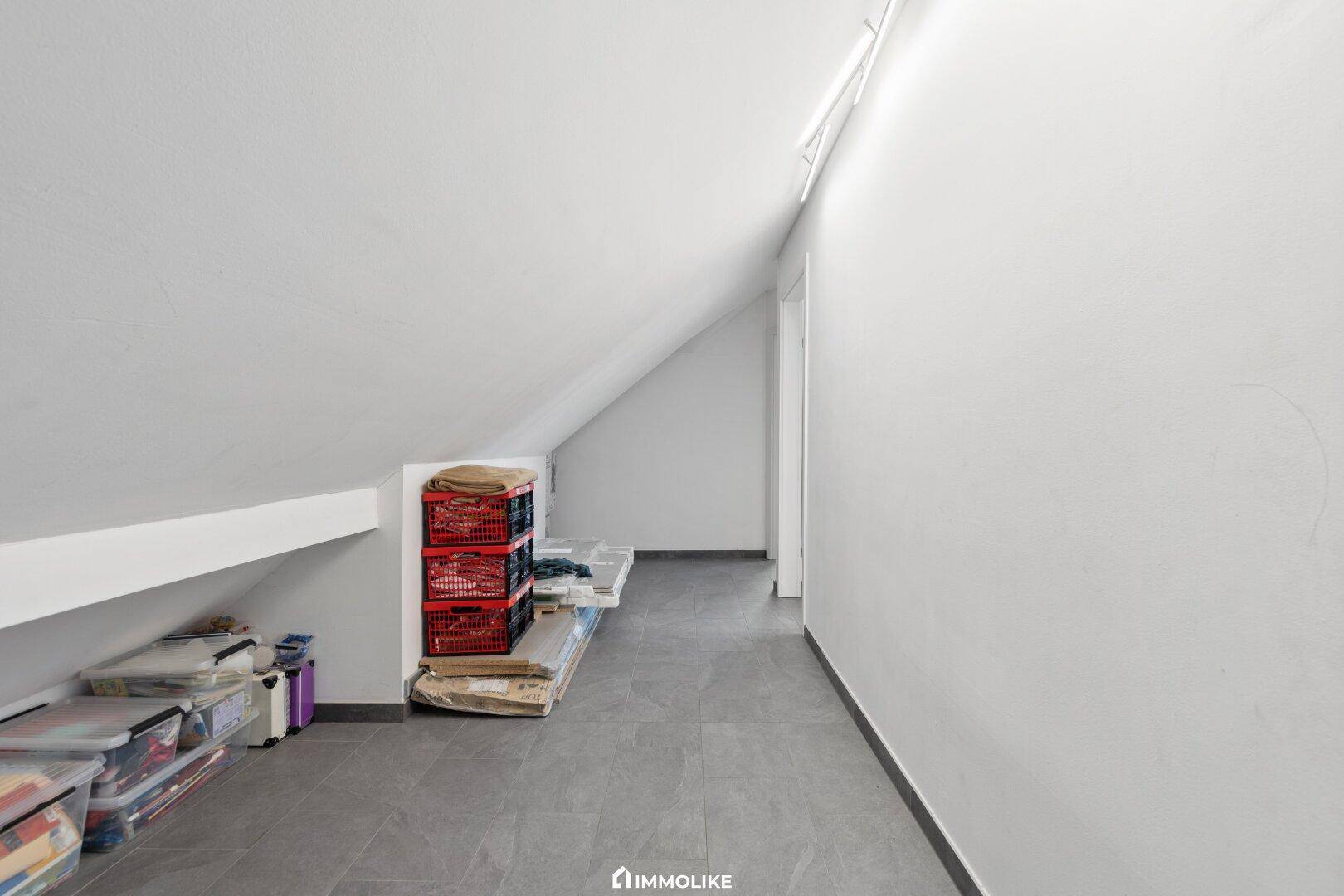 Dachboden als Abstellraum genutzt mit schrägen Wänden und grauem Fliesenboden.