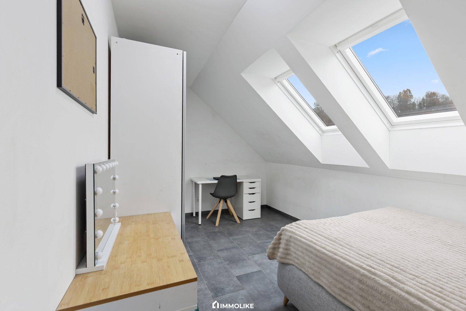 Dachgeschoss-Schlafzimmer mit zwei Dachfenstern, Schreibtisch und modernem Dekor.