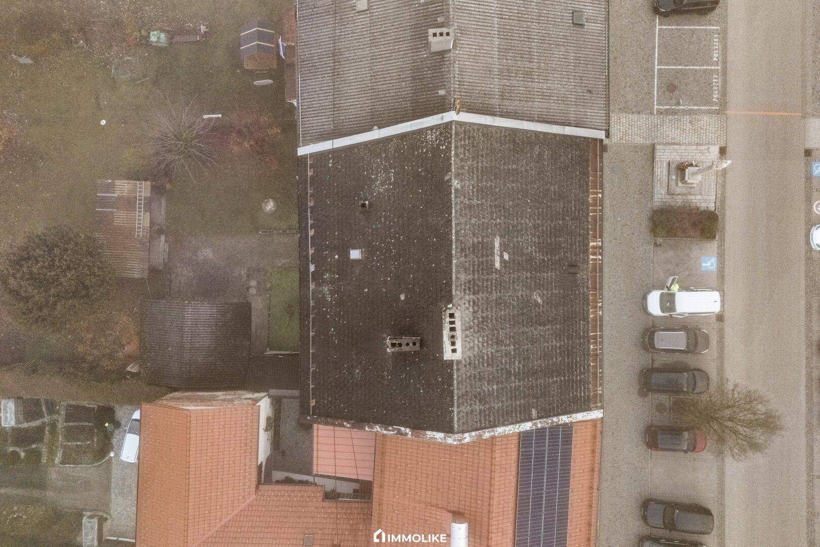 Senkrechte Luftaufnahme der Dächer der Gebäude und des angrenzenden Parkplatzes.