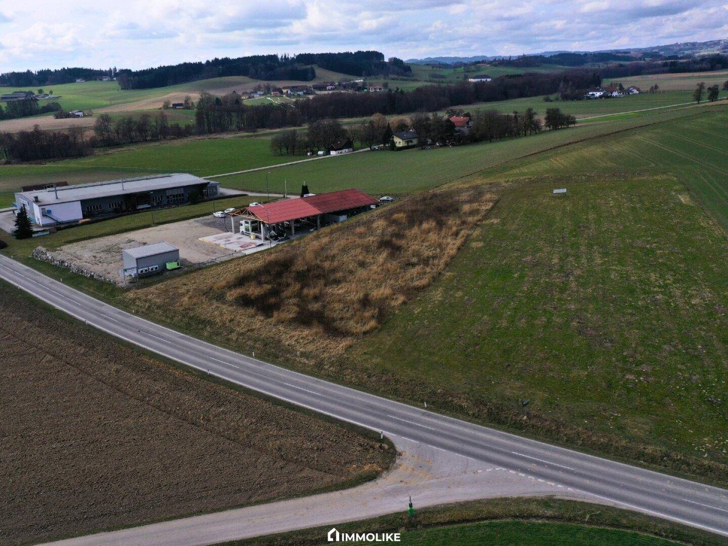 Luftaufnahme des Anwesens mit rotem Dach, einem weiteren Industriegebäude, Feldern und einer Landstraße in ländlicher Umgebung.