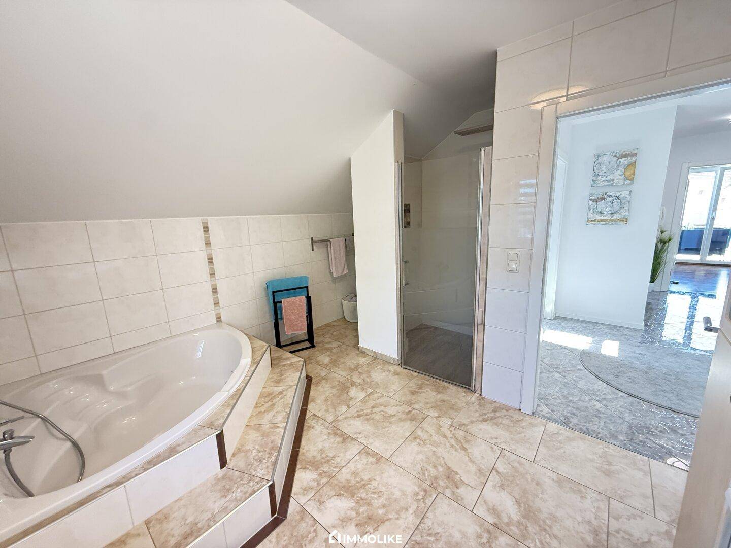 Geräumiges Badezimmer mit Badewanne, separater Dusche und hellen Fliesen.
