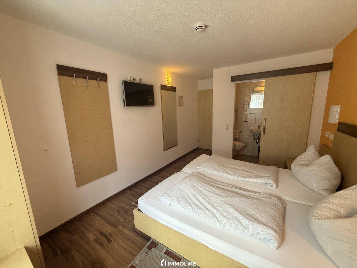 Schlafzimmer mit Doppelbett und Zugang zu einem Badezimmer durch eine Schiebetür.