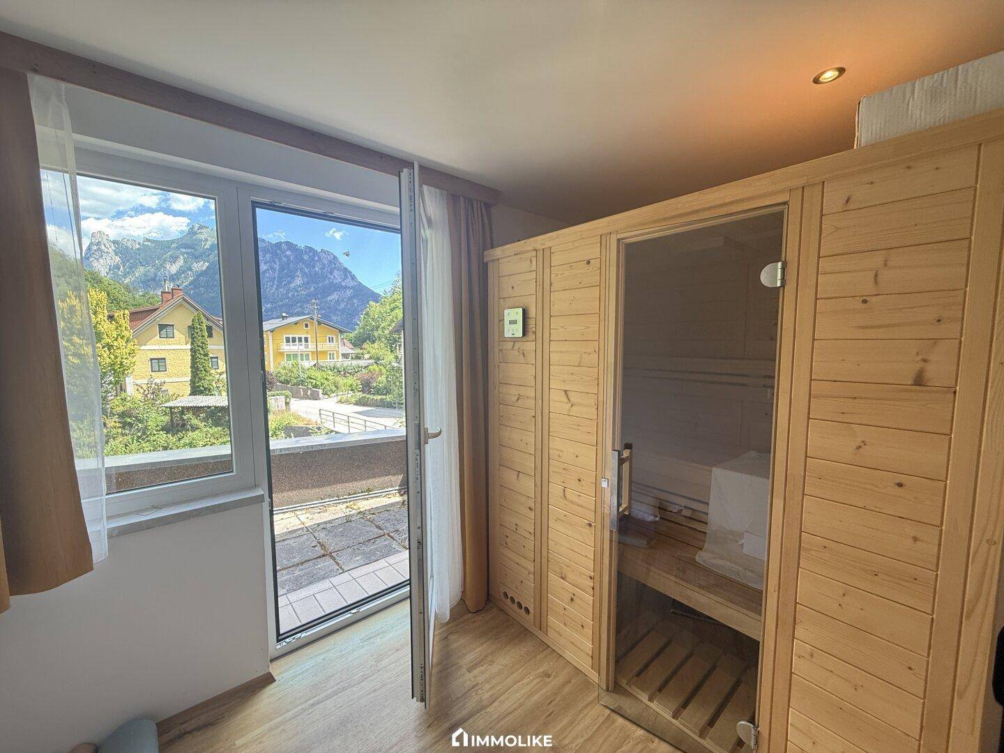 Wellnessbereich mit Sauna und Zugang zu einem Balkon mit Bergblick.