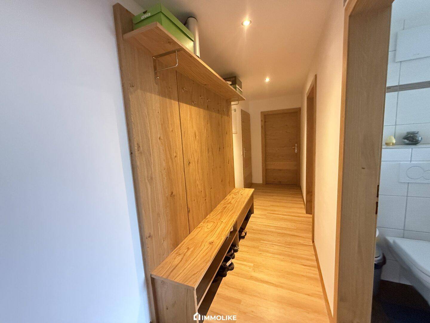 Heller Eingangsbereich mit Garderobe aus Holz und Ablageflächen.