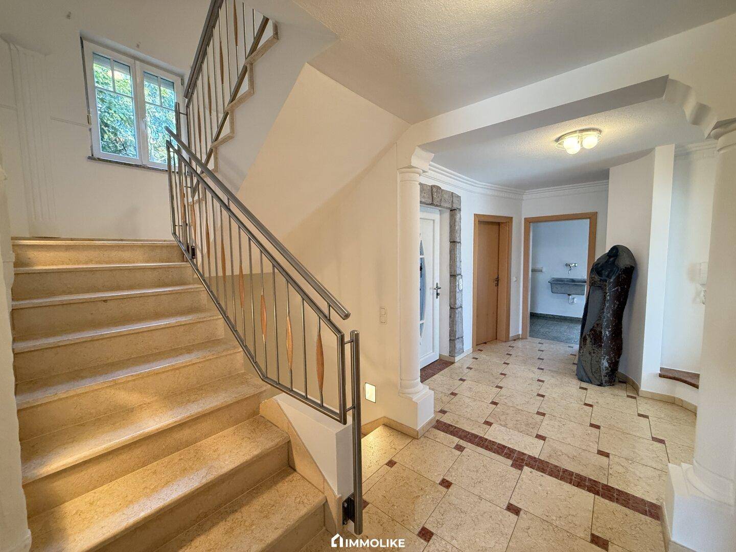 Geräumiger Eingangsbereich mit eleganter Steintreppe und gemustertem Fliesenboden.