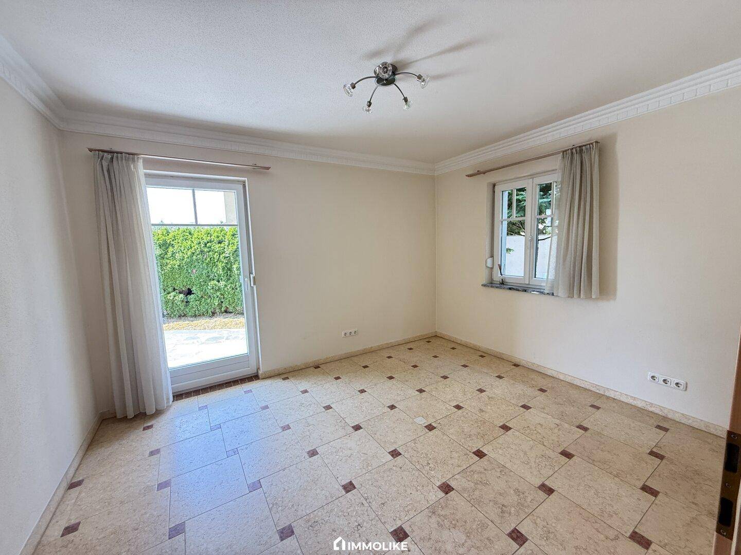 Helles Schlafzimmer mit Fliesenboden und direktem Zugang zu einem Balkon oder einer Terrasse.