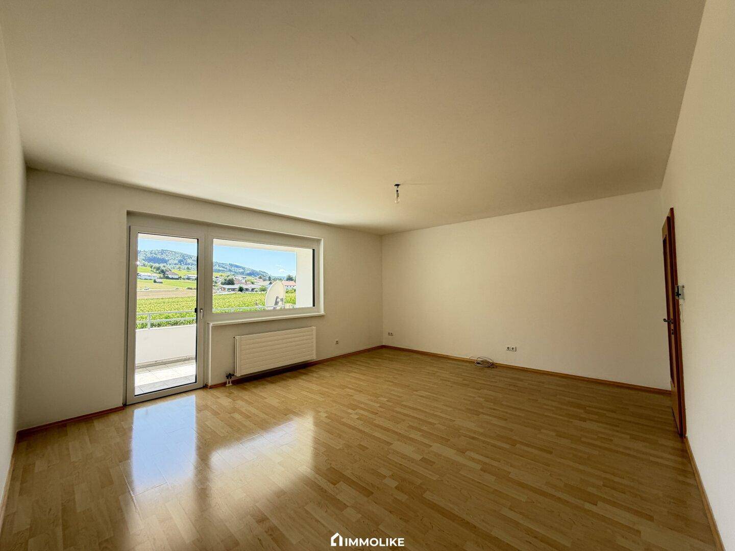 Lichtdurchflutetes Zimmer mit Holzboden und direktem Zugang zum Balkon, ideal für entspannte Stunden.