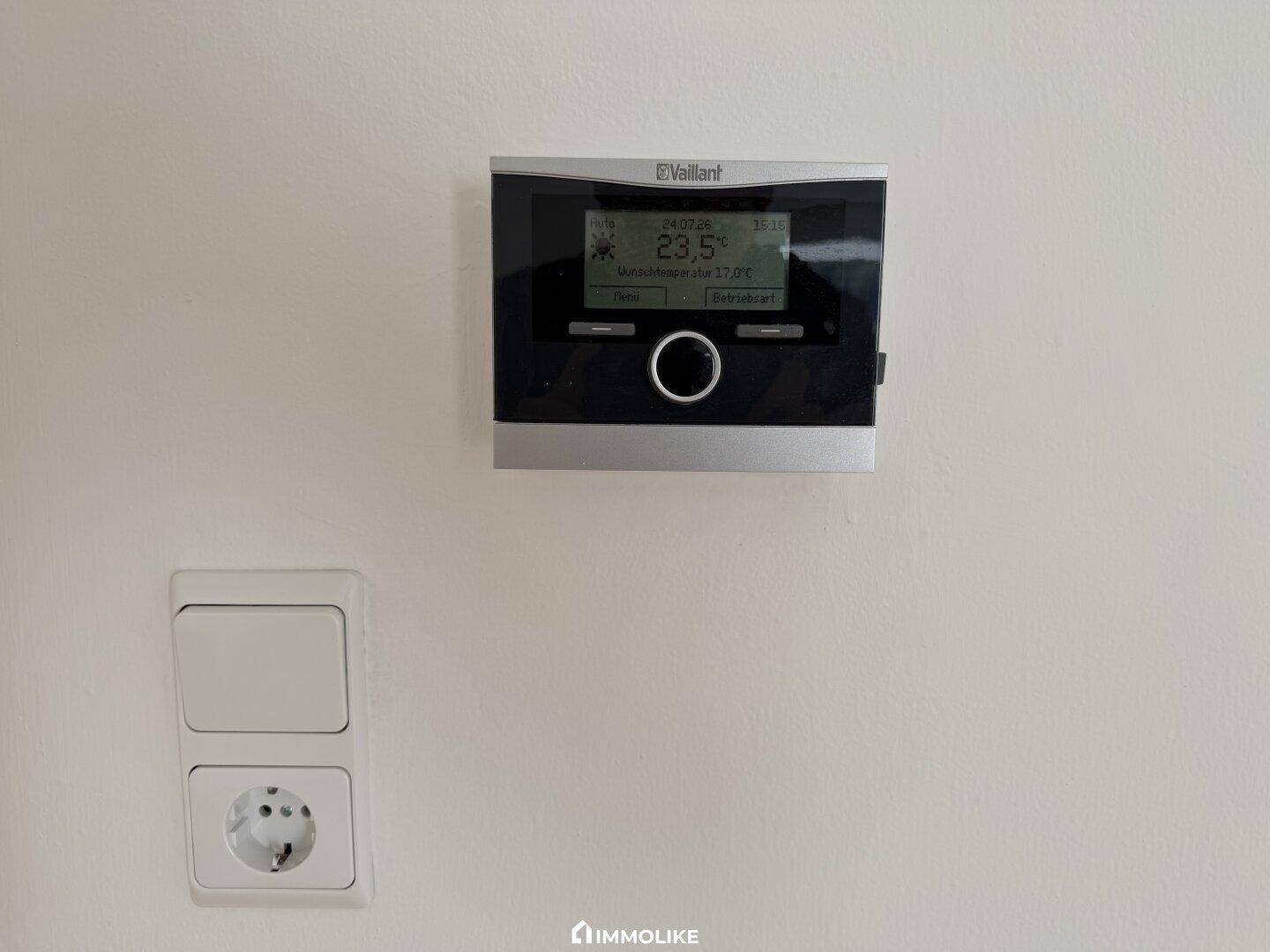 Modernes Vaillant-Thermostat zur Heizungssteuerung und eine Steckdose an der Wand.