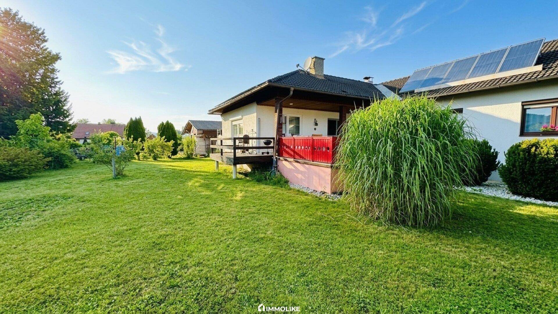 Hinterer Gartenbereich mit kleiner Holzterrasse und Blick auf die grüne Umgebung.