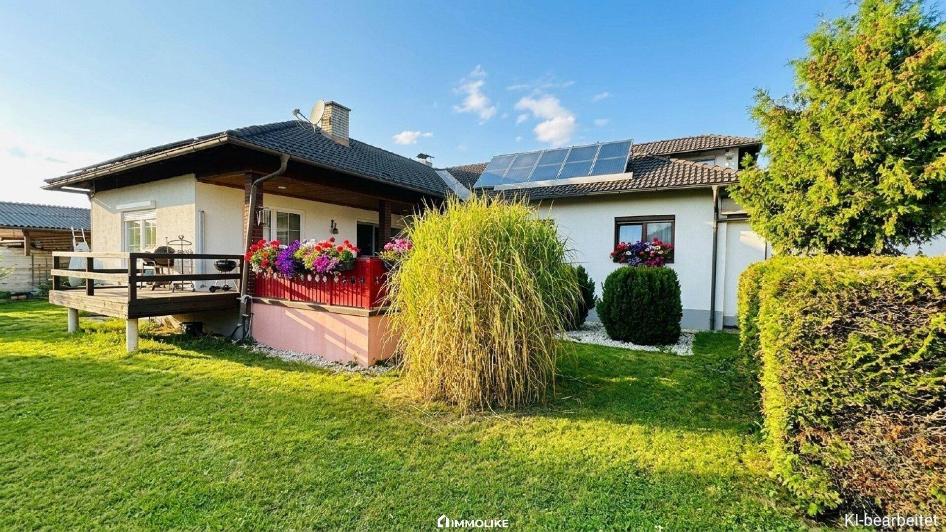 Hinterer Gartenbereich mit Rasenfläche, Terrasse und Solaranlage auf dem Dach.