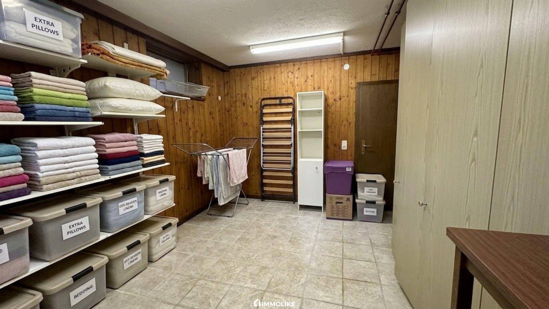 Praktischer Hauswirtschaftsraum mit Holzvertäfelung, Regalen für Wäsche und einem Wäscheständer.