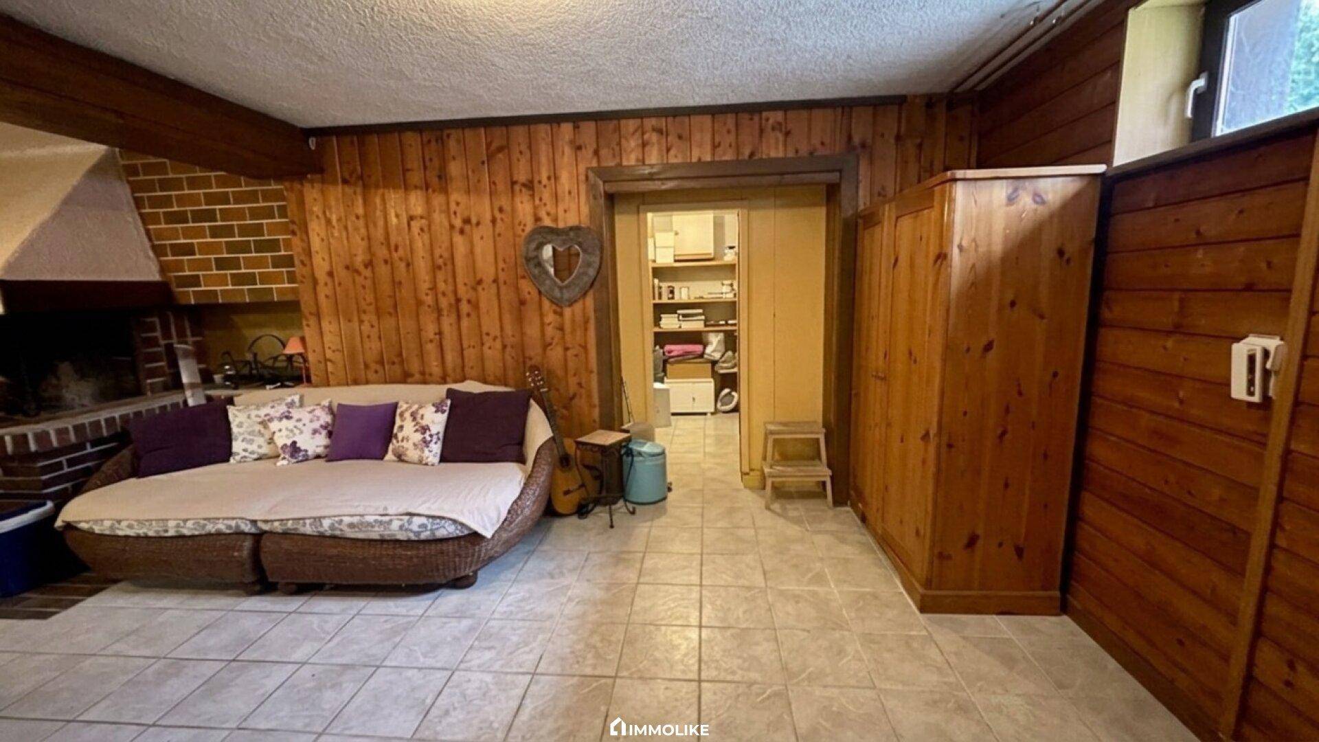Wohnzimmer mit Holzvertäfelung, Fliesenboden, Kamin und einem bequemen Sofa.