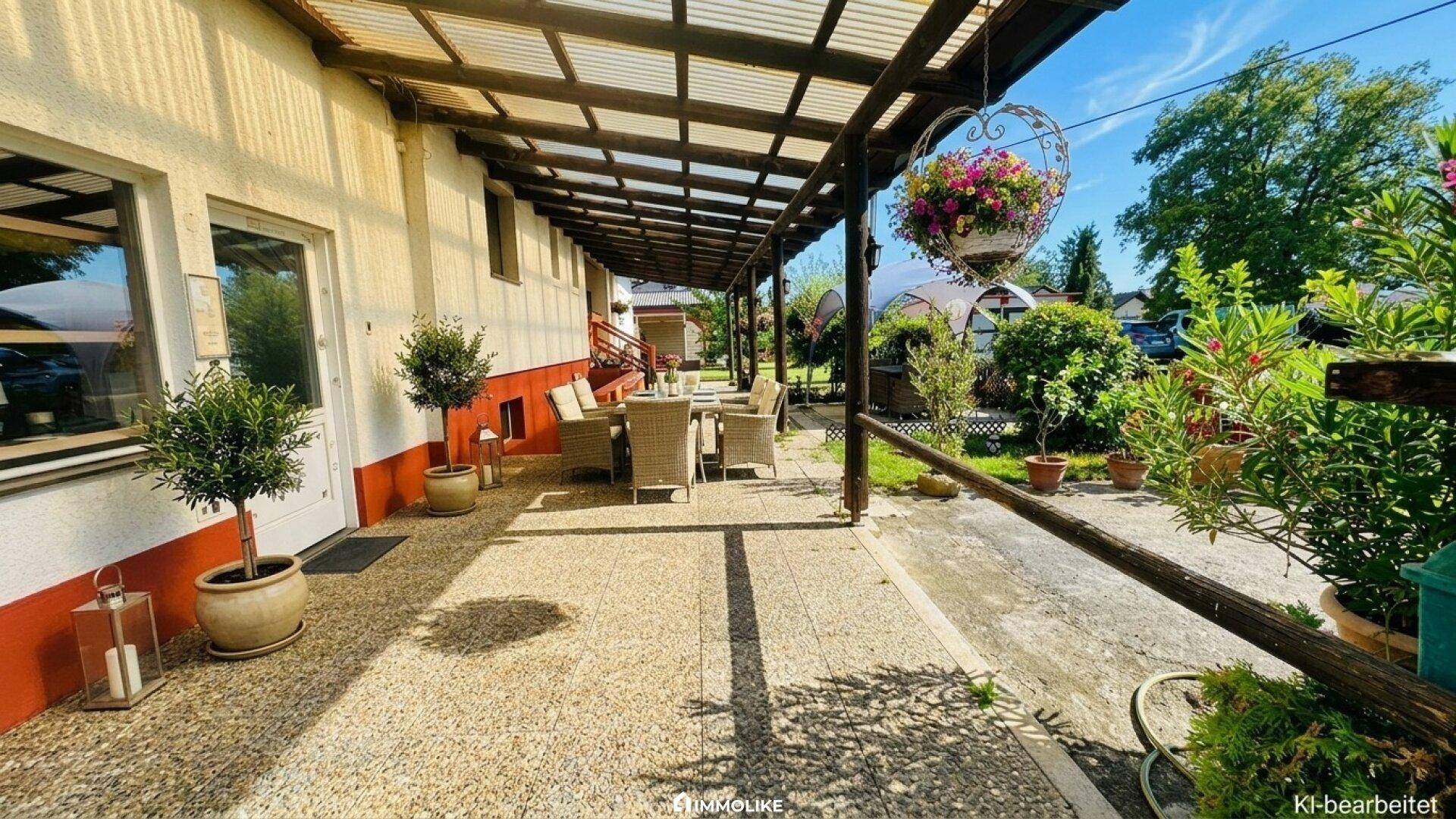 Lange überdachte Terrasse mit Essbereich und Blick in den grünen Garten.