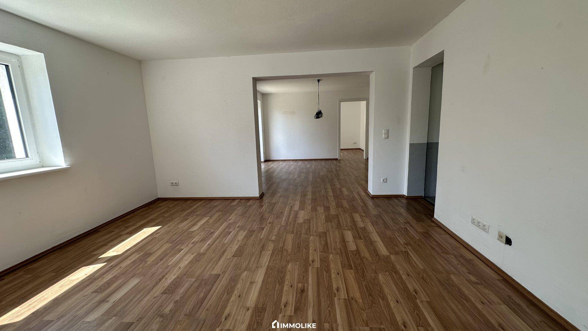 Heller, leerer Raum mit Laminatboden und weißen Wänden, ideal als Wohn- oder Essbereich.