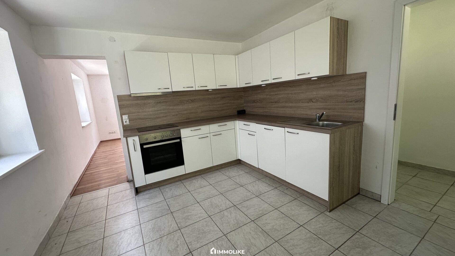 Geräumige Einbauküche mit weißen Fronten, integriertem Backofen und viel Stauraum.