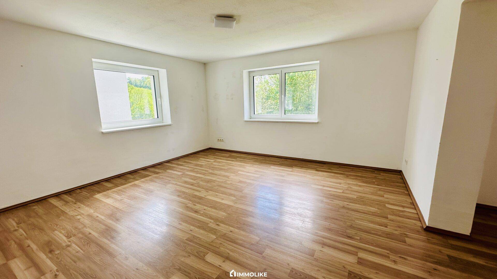 Geräumiger, heller Raum mit Laminatboden und zwei Fenstern, ideal als Schlaf- oder Kinderzimmer.