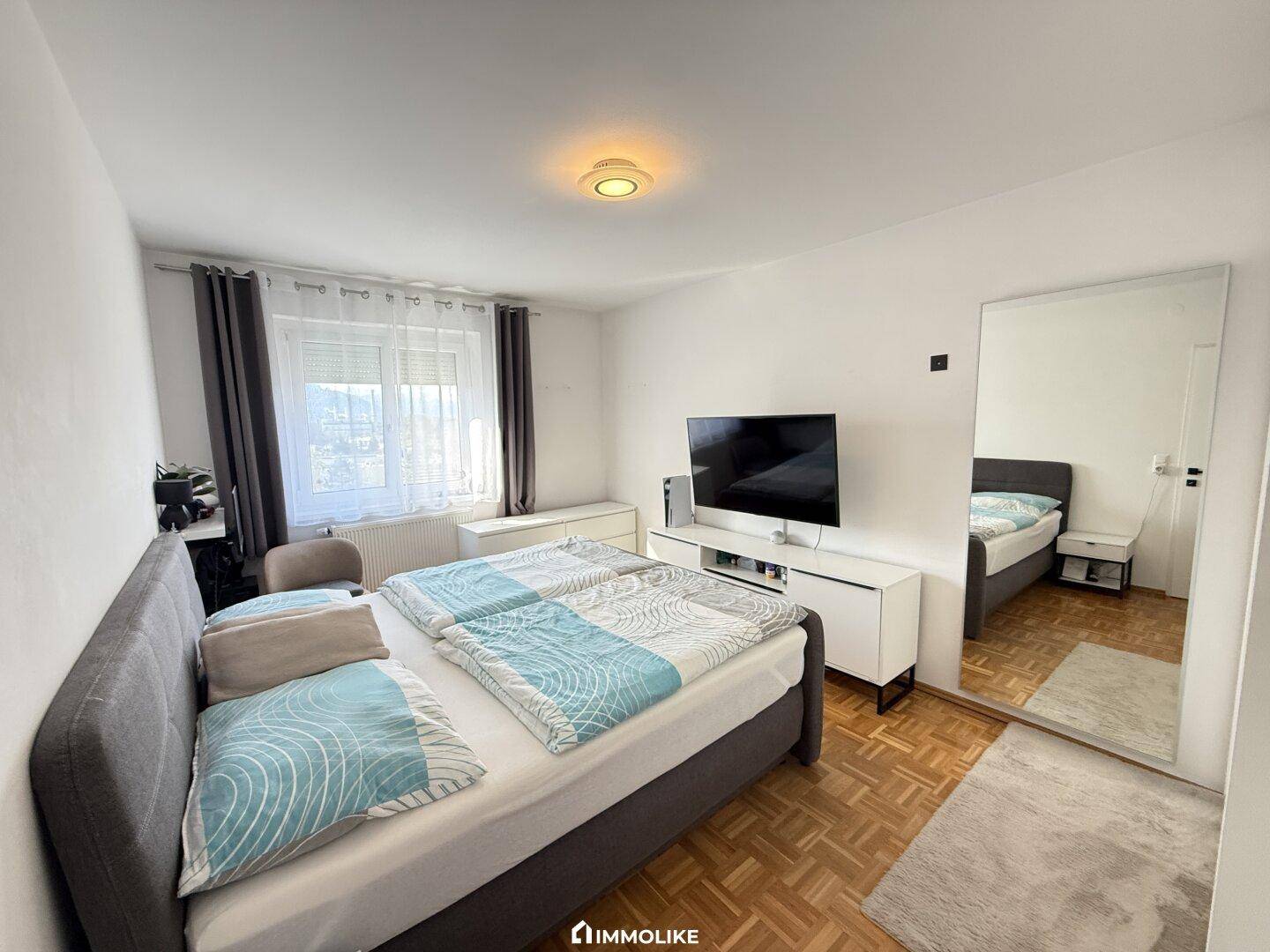 Gemütliches Schlafzimmer mit Doppelbett, Fernseher und großem Spiegel.
