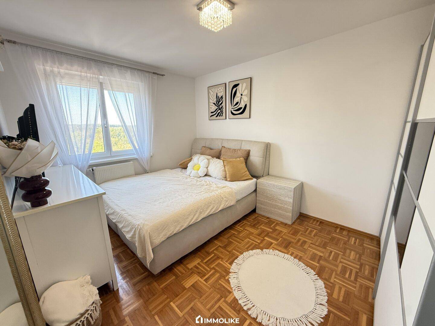 Freundliches Schlafzimmer mit Doppelbett, Nachttischen und Blick ins Grüne.