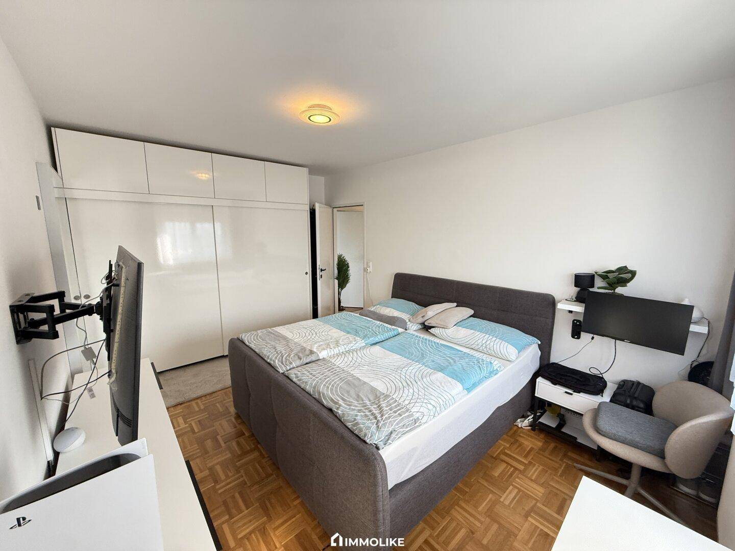 Helles Schlafzimmer mit Doppelbett, weißen Schränken und modernem Dekor.