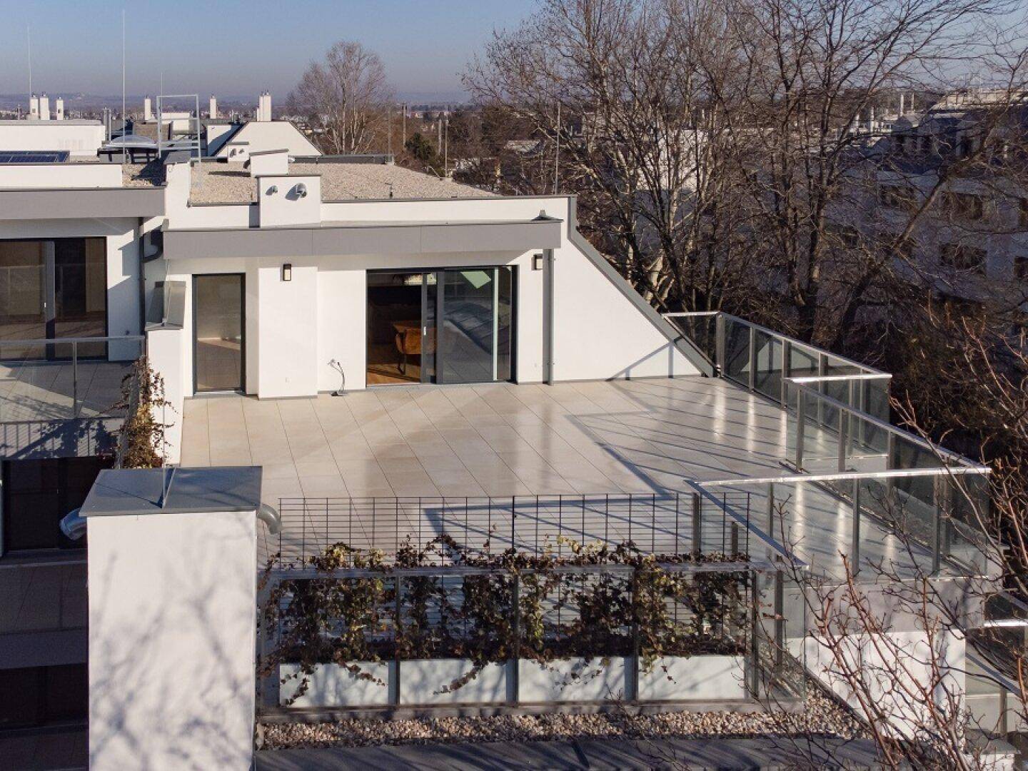 Weitläufige Dachterrasse mit Glasgeländer und Blick auf die umliegende Bebauung.