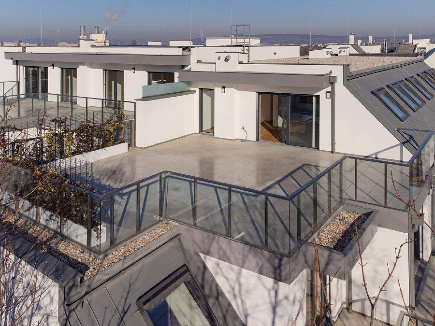 Dachlandschaft mit mehreren Terrassenbereichen und moderner Architektur des Gebäudes.