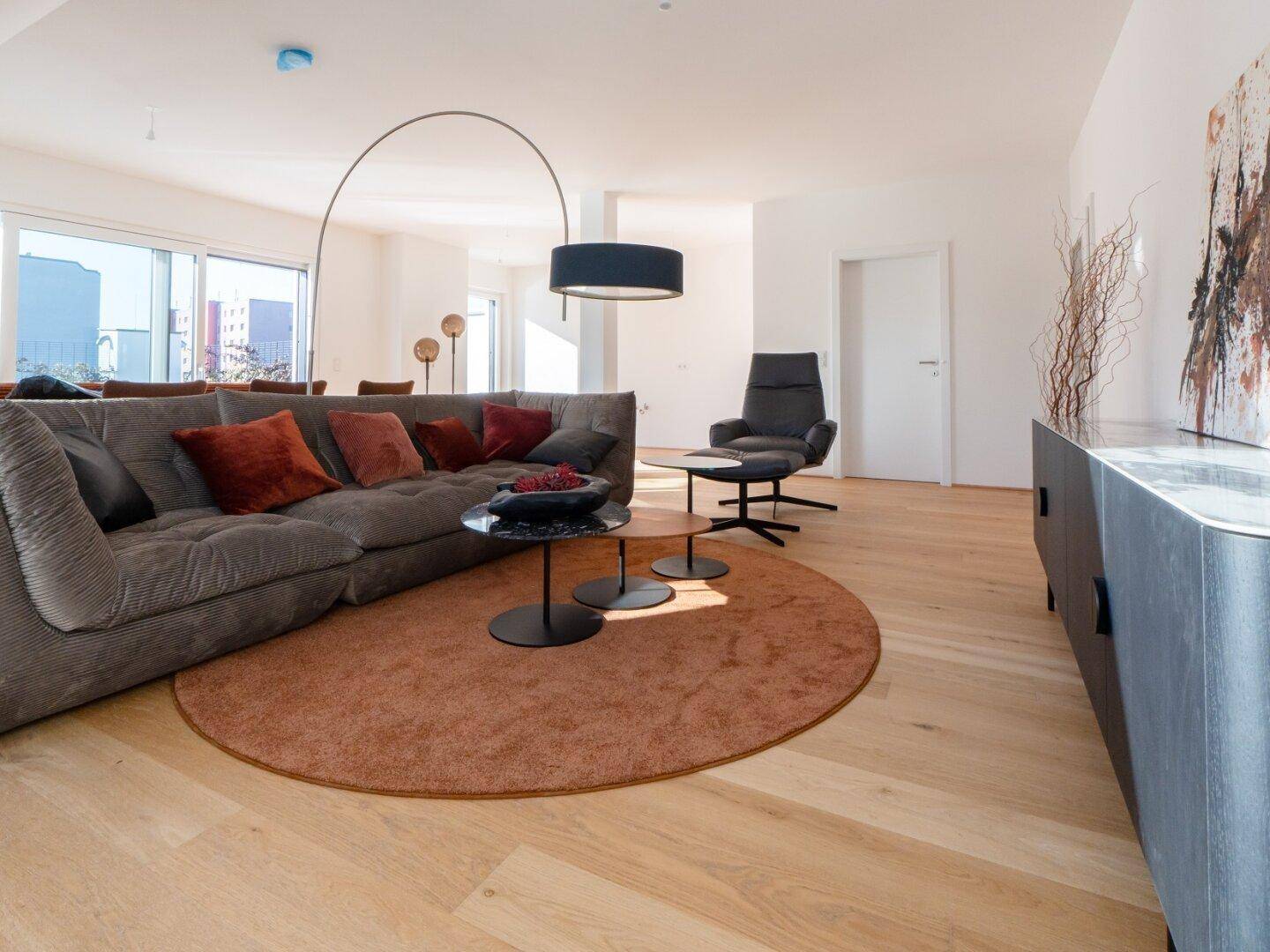 Modern eingerichtetes Wohnzimmer mit bequemer Couch, Holzboden und zeitgenössischer Kunst.