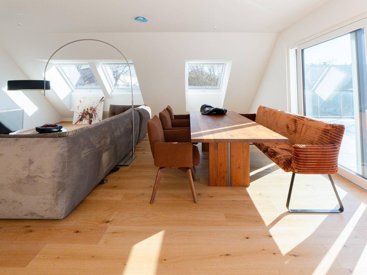 Heller Wohnbereich mit Dachschrägen, Holzboden und stilvoller Einrichtung, Essbereich sichtbar.