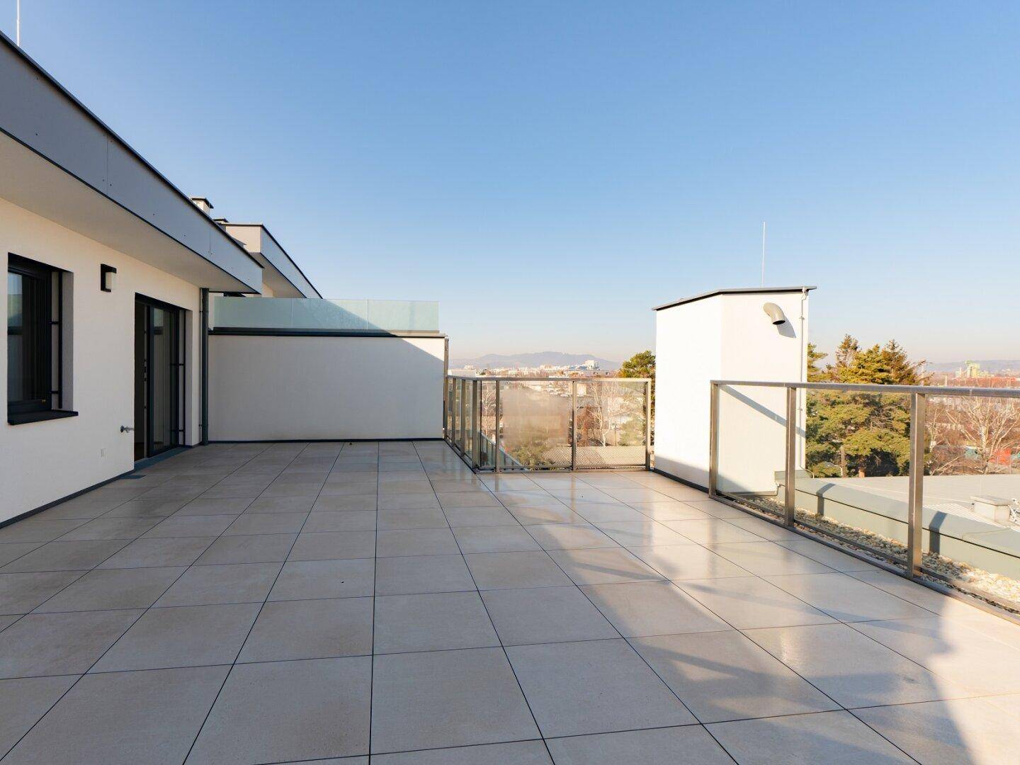 Große Dachterrasse mit Fliesenboden und weitem Blick über die Stadtlandschaft.