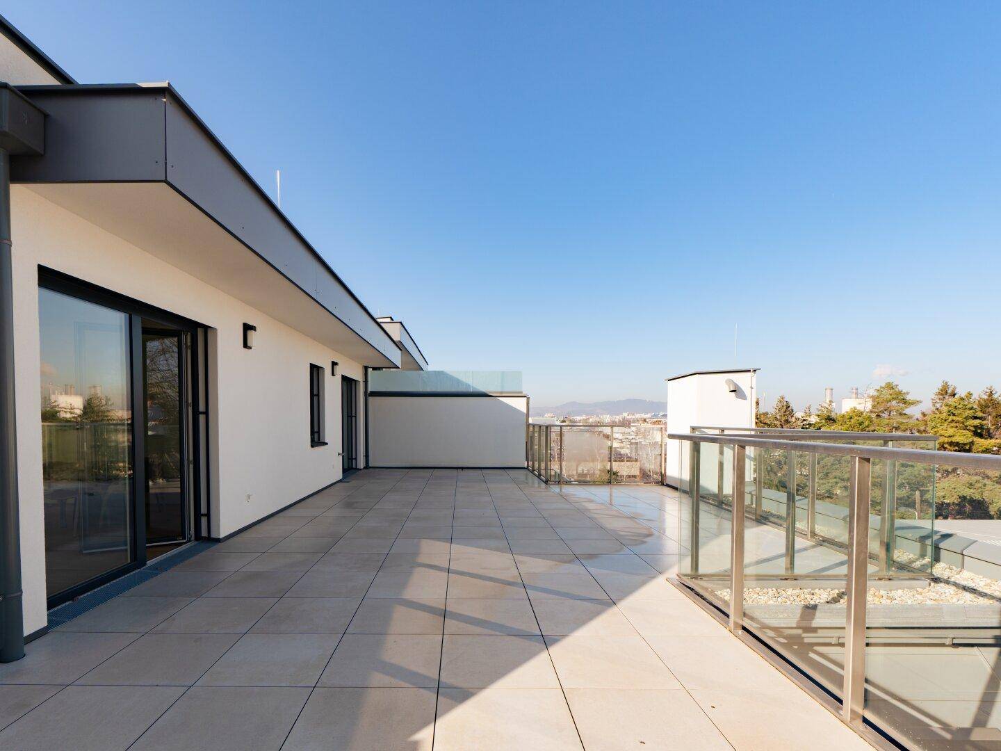 Große Dachterrasse mit Fliesenboden und weitem Blick über die Stadtlandschaft.