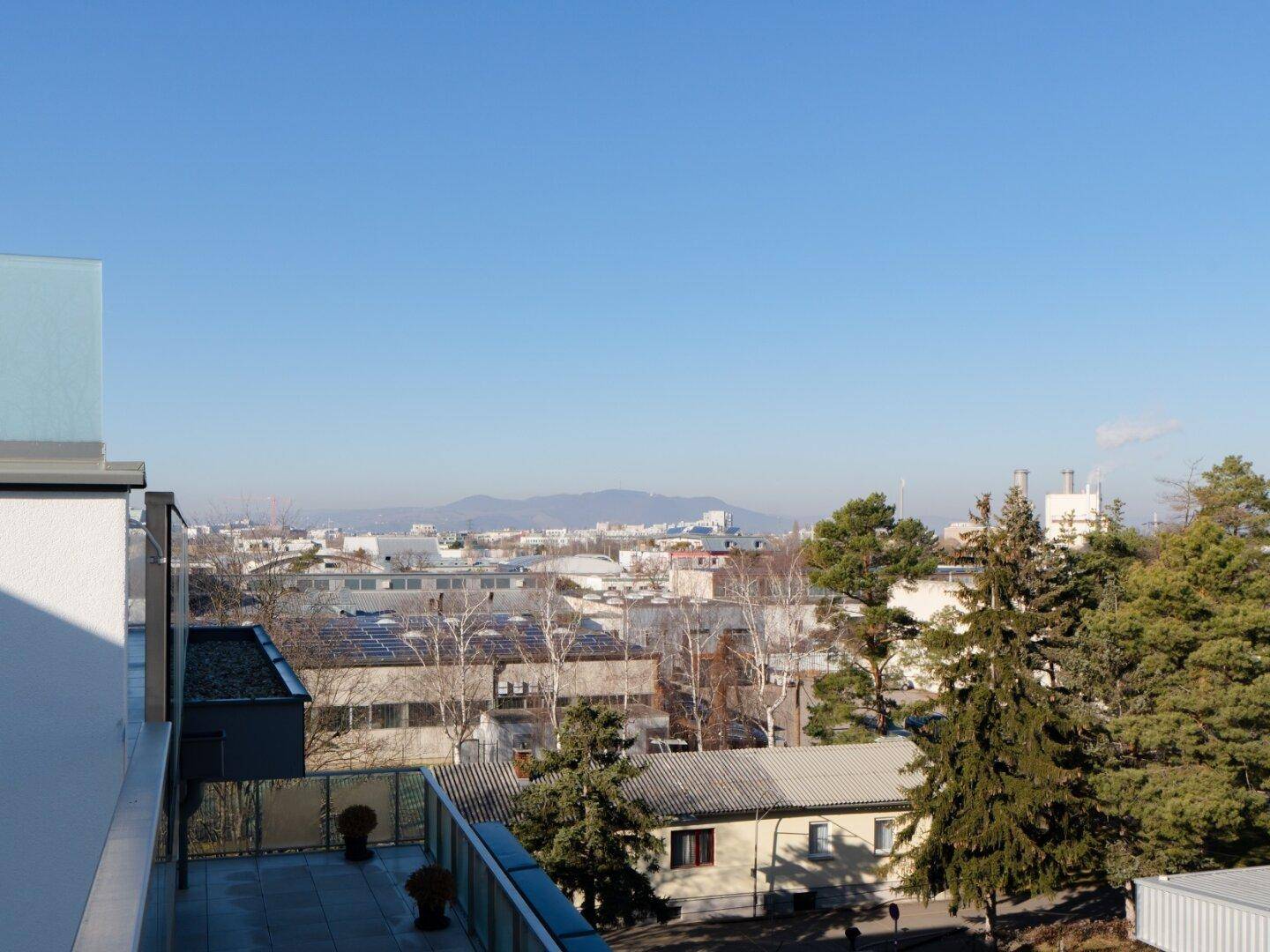 Panoramablick über die Stadt mit Bergen im Hintergrund unter klarem blauem Himmel.