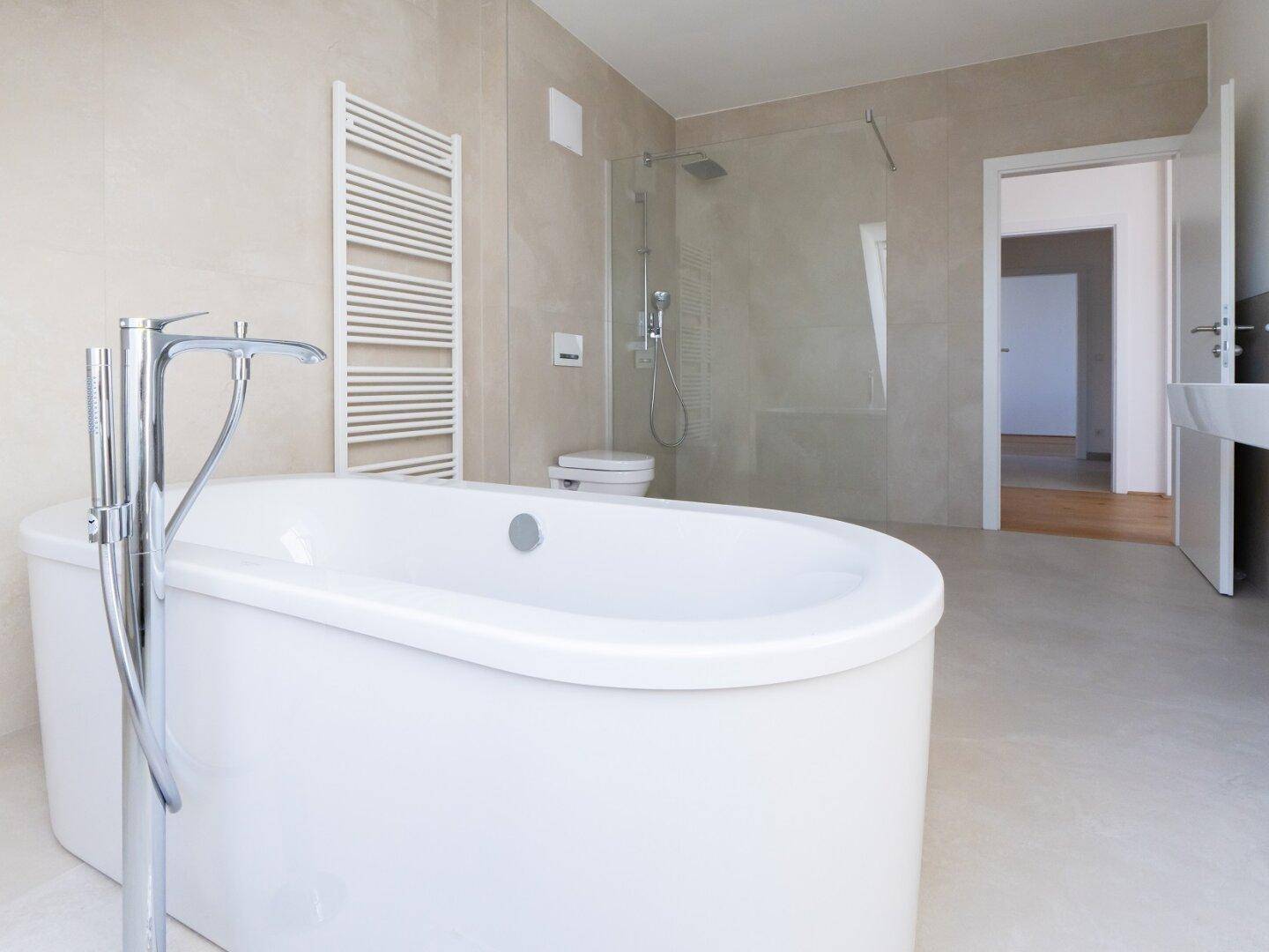 Modernes Badezimmer mit freistehender Badewanne und begehbarer Dusche, hell gefliest.