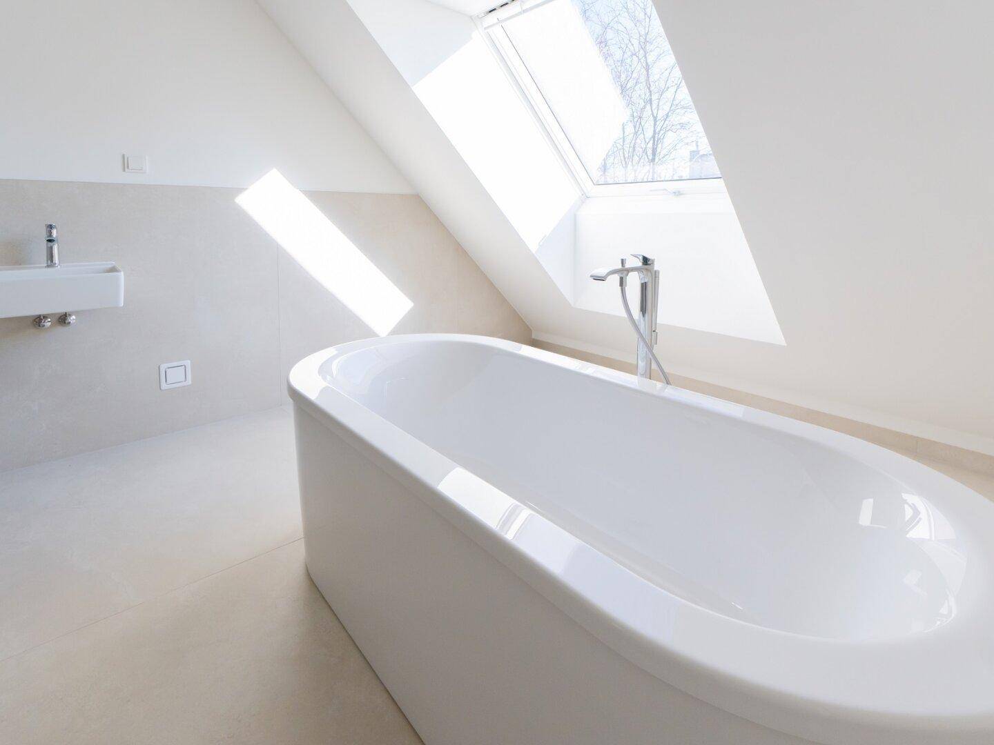 Helles Badezimmer mit freistehender Badewanne, Dachfenster und modernen Fliesen.
