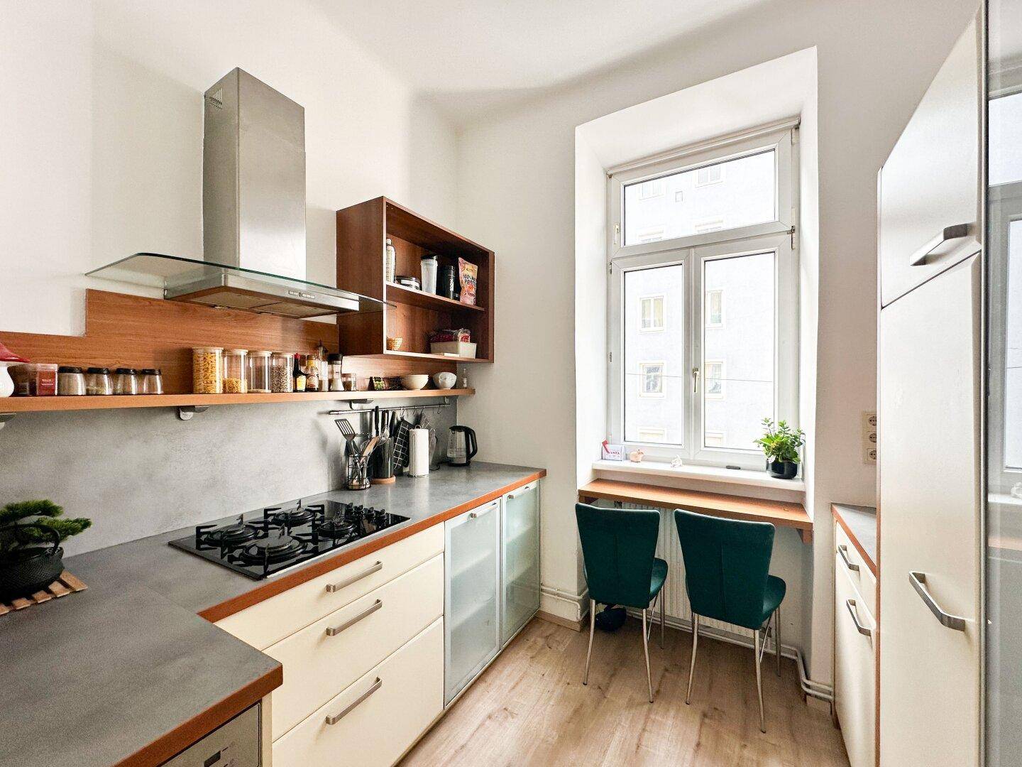 Moderne Küche mit Gasherd, Holzregalen, hellen Schränken und einem Fenster mit kleiner Sitzgelegenheit.