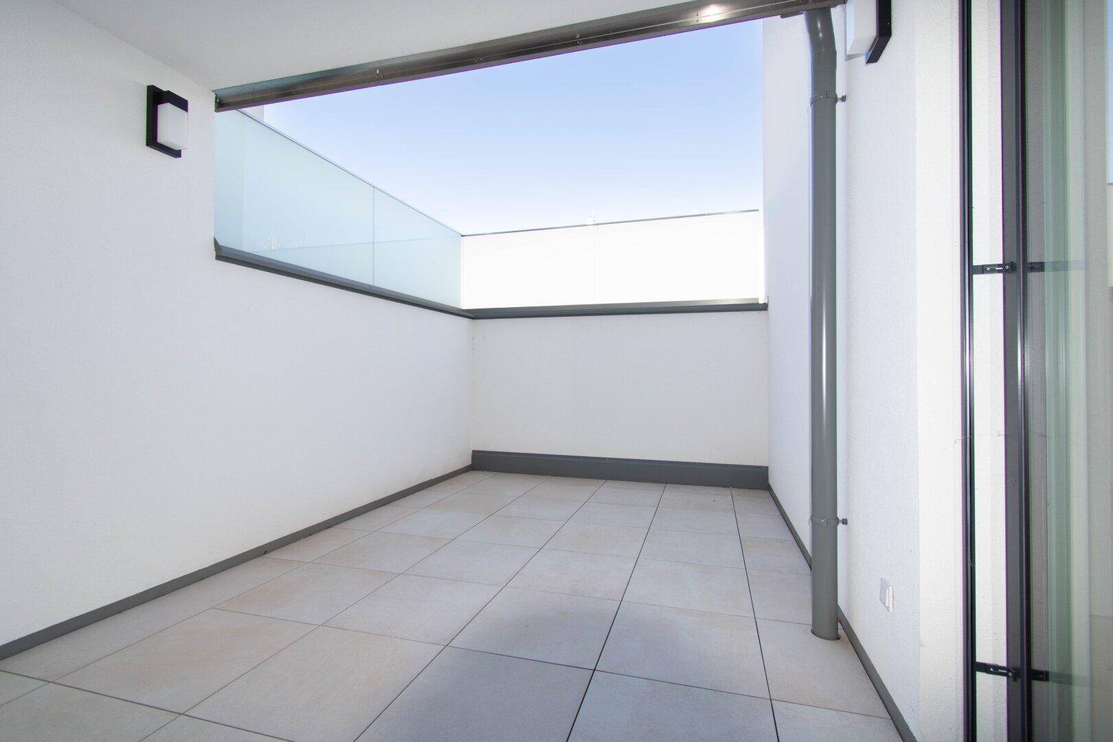 Heller Balkon mit Fliesenboden und Glasbrüstung, ideal für entspannte Stunden im Freien.