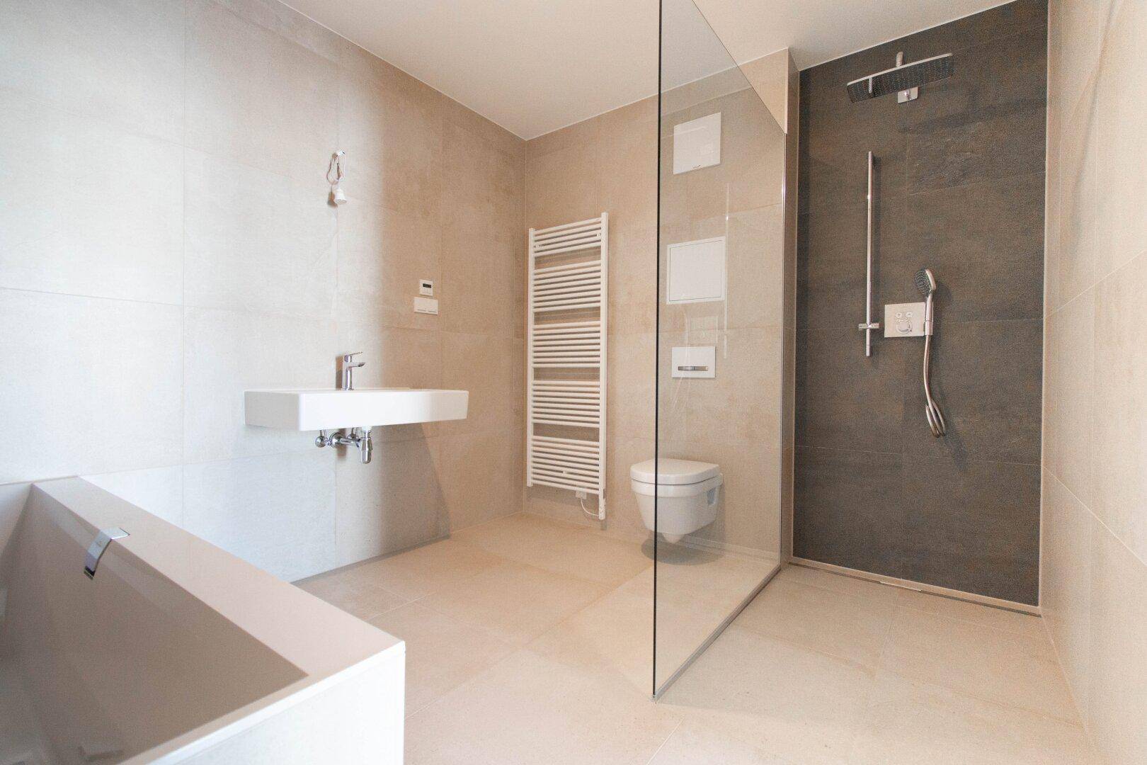 Modernes Badezimmer mit begehbarer Dusche, Badewanne und hellen Fliesen.