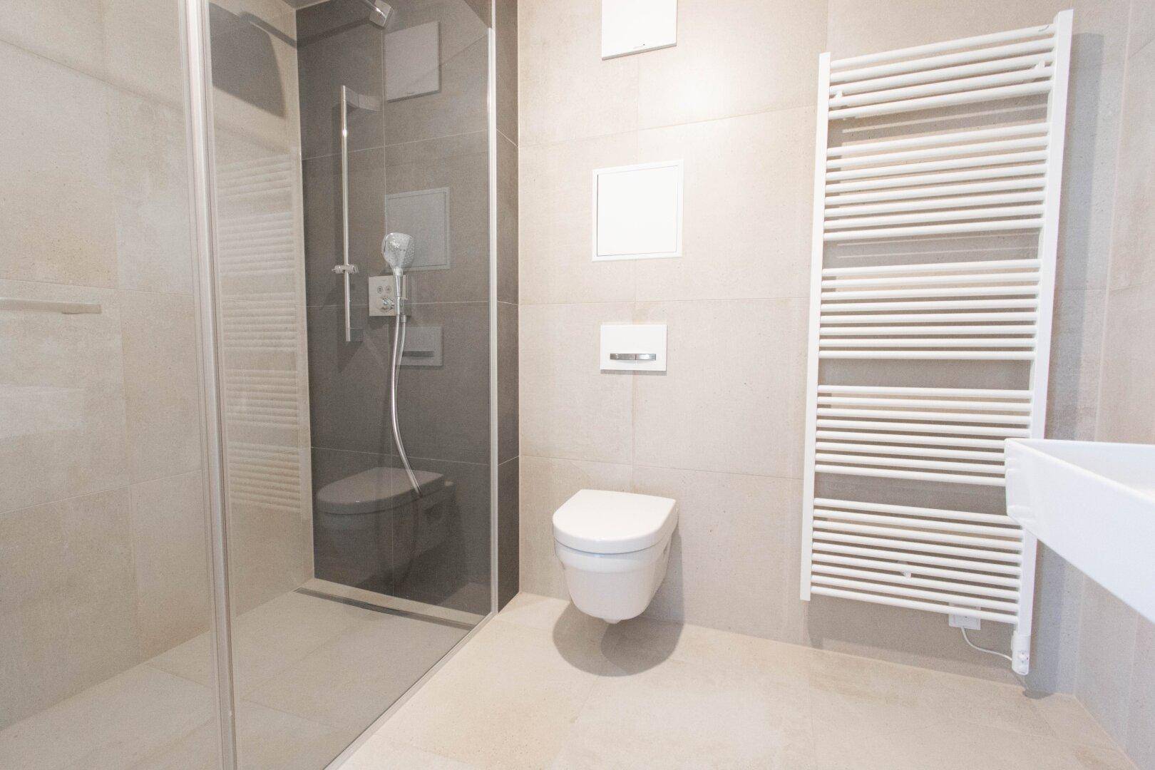 Modernes Badezimmer mit begehbarer Dusche, Wand-WC und beheiztem Handtuchhalter.