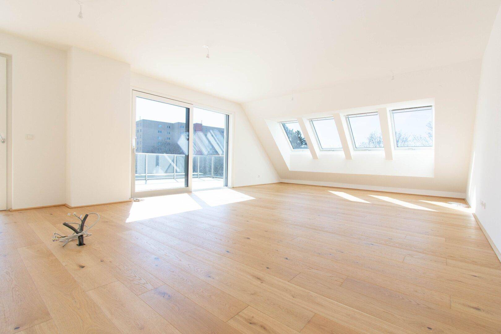 Heller Wohnraum mit Holzboden, großen Schiebetüren zur Terrasse und Dachfenstern für viel Licht.