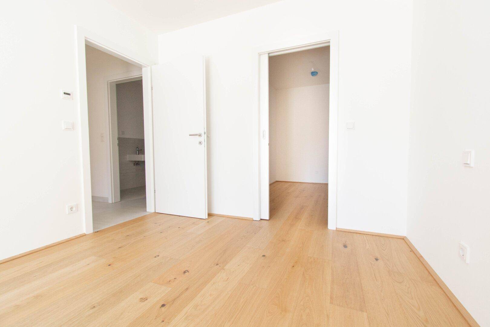 Heller Flur mit Holzboden, der zu weiteren Zimmern und einem Badezimmer führt.