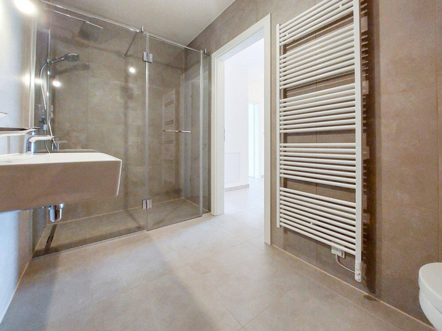 Modernes Badezimmer mit ebenerdiger Dusche, Einzelwaschbecken und Handtuchheizkörper.