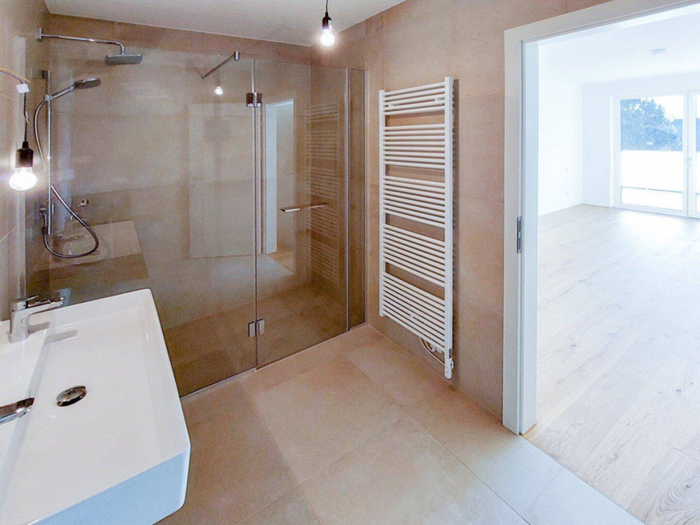 Modernes Badezimmer mit ebenerdiger Dusche, Einzelwaschbecken und beheiztem Handtuchhalter.