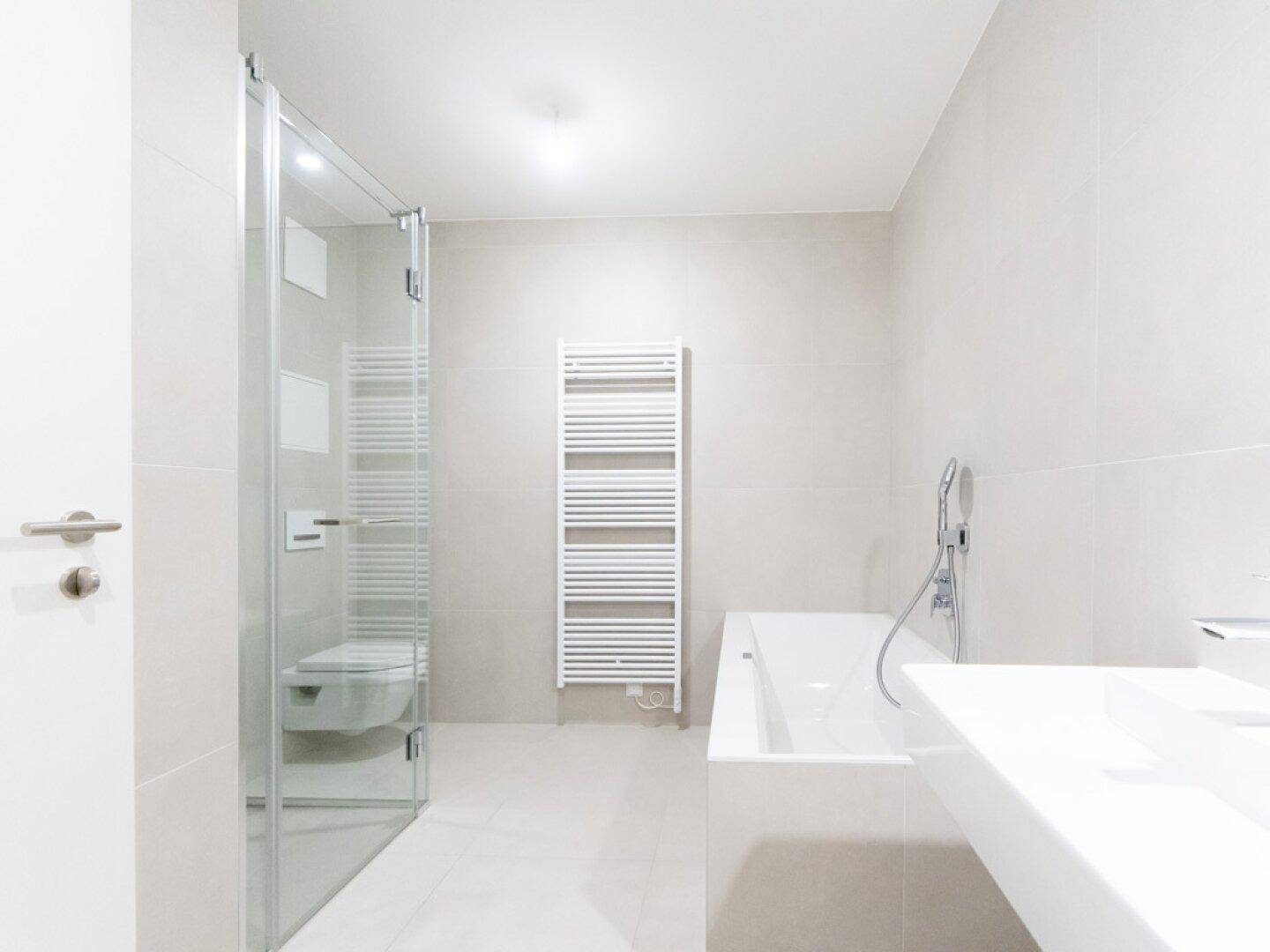 Modernes Badezimmer mit Dusche, Badewanne, Einzelwaschbecken und beheiztem Handtuchhalter.