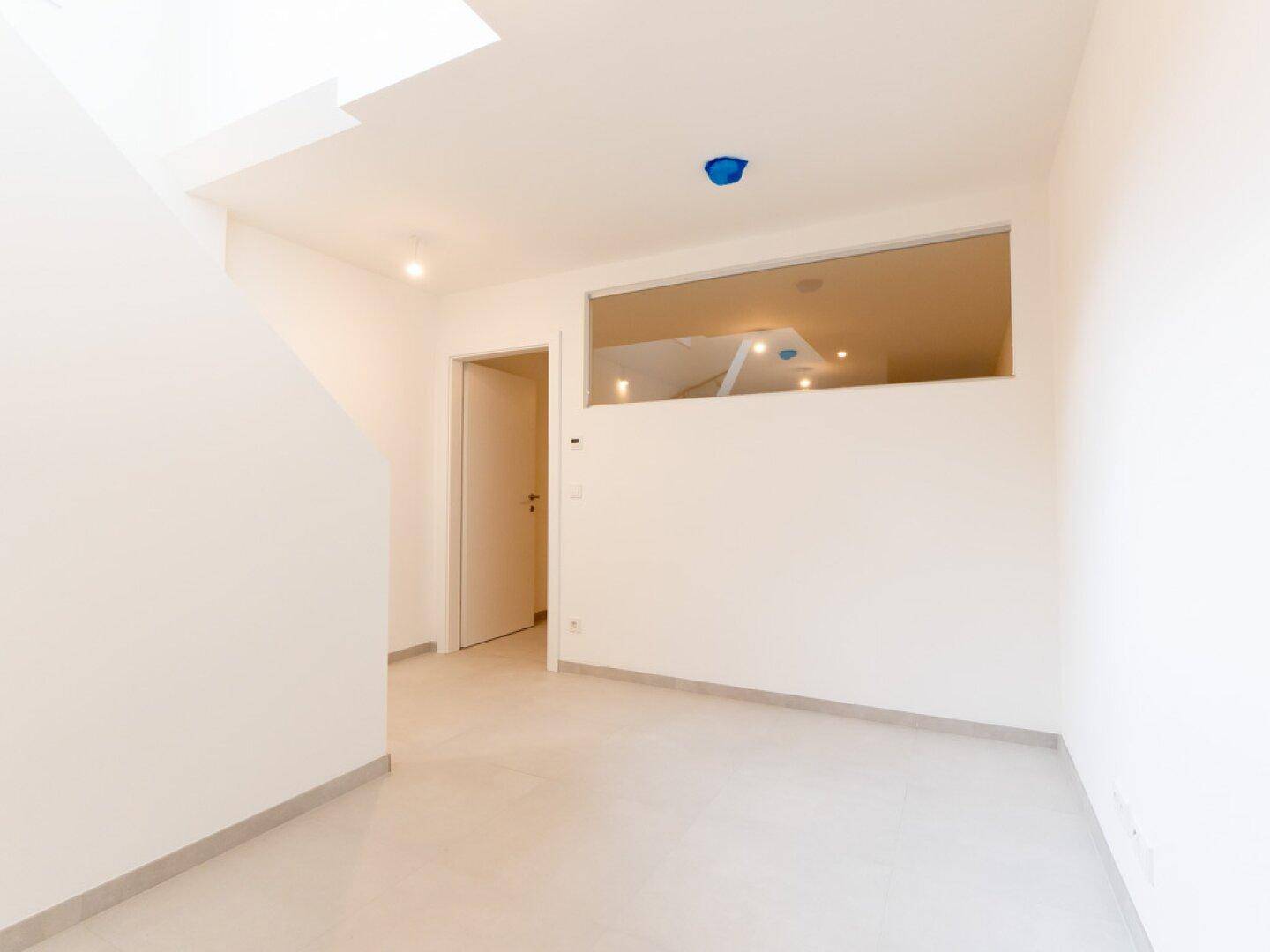 Heller Raum mit Fliesenboden und einem hohen Fenster, möglicherweise ein Hauswirtschaftsraum.