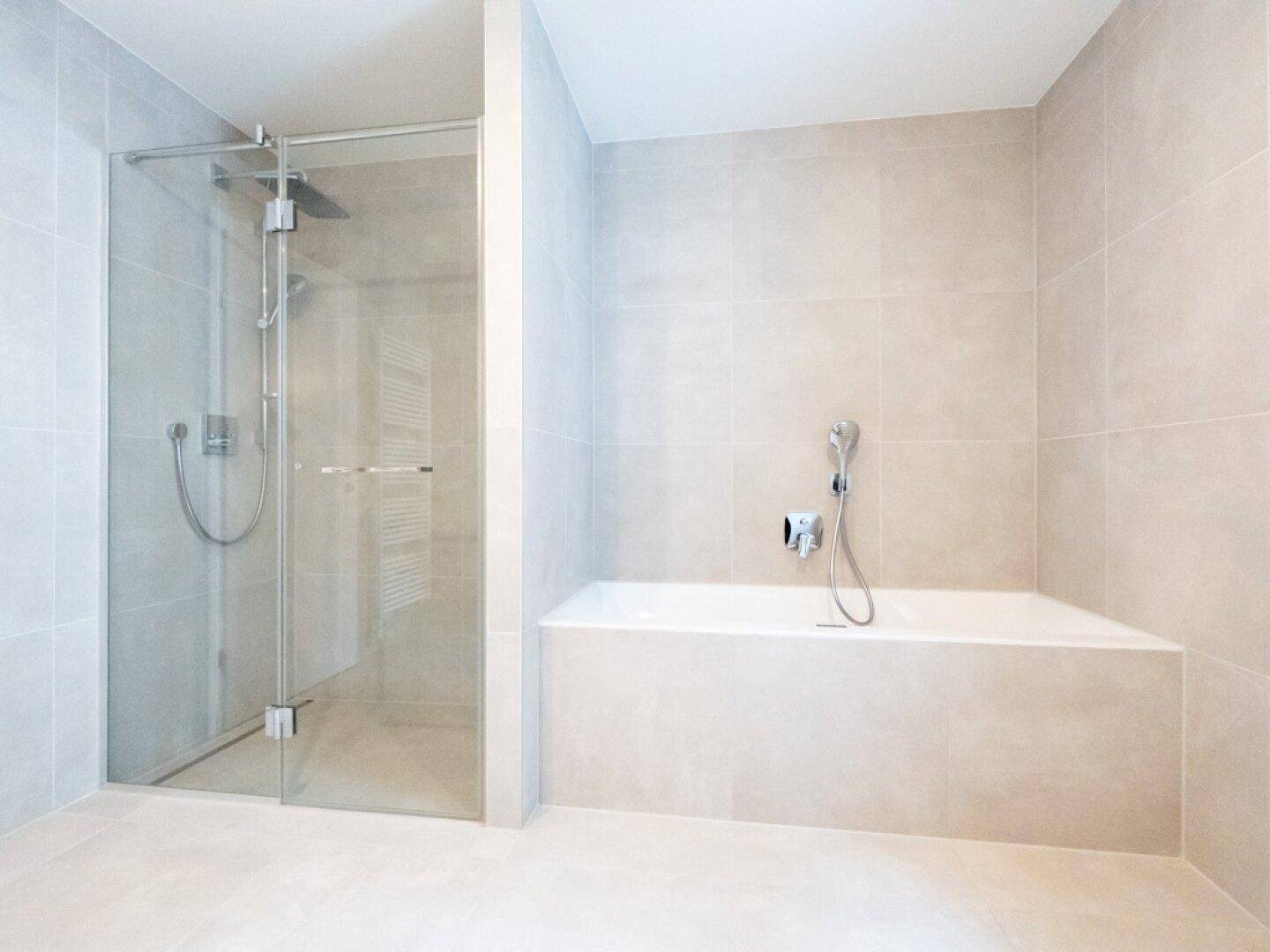 Elegantes Badezimmer mit beigen Fliesen, integrierter Badewanne und geräumiger Glasdusche.