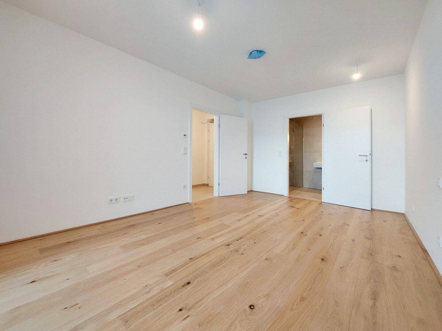 Heller Raum mit Holzboden und Zugang zu weiteren Zimmern, ideal für individuelle Gestaltung.