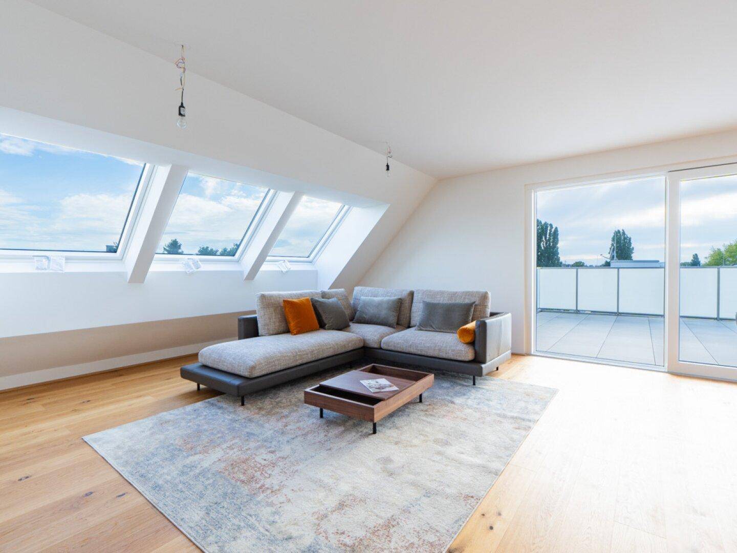 Gemütlicher Wohnbereich mit Sofa, Holzboden, Dachschrägen und großen Dachfenstern.